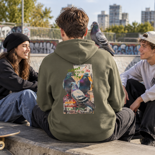 Eine Gruppe junger Erwachsener in einem Skatepark. Ein Mann mit dem Rücken zu m Betrachter trägt einen grünen Hoodie mit dem Aufdruck von 3 Tauben und dem Slogan "respect our life - Tauben". Auf seiner Schulter sitzt eine Stadttaube.
