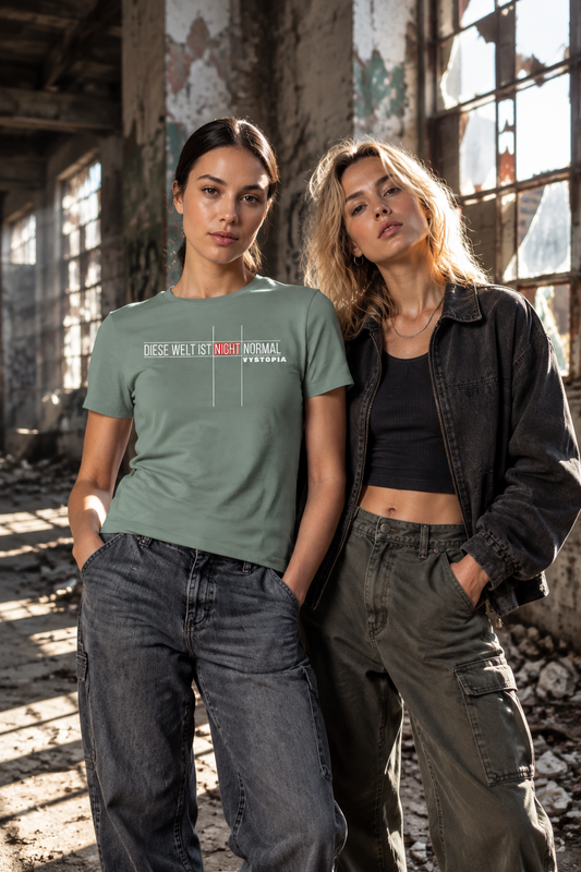 Zwei junge Frauen in einer lost place scenery. Die Frau links im Bild trägt ein olivefarbenes T-Shirt mit dem Print "Diese Welt ist nicht normal. Vystopia"